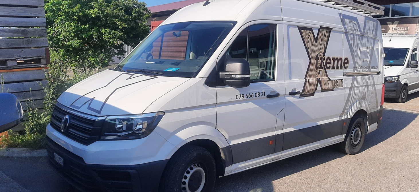 Une camionnette blanche avec un le logo Xtreme Charpente garée sur un parking.