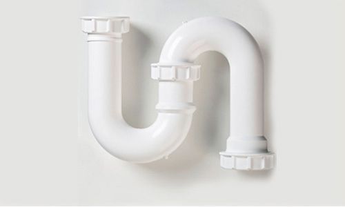 Un tubo de plástico blanco está apoyado sobre una pared blanca.