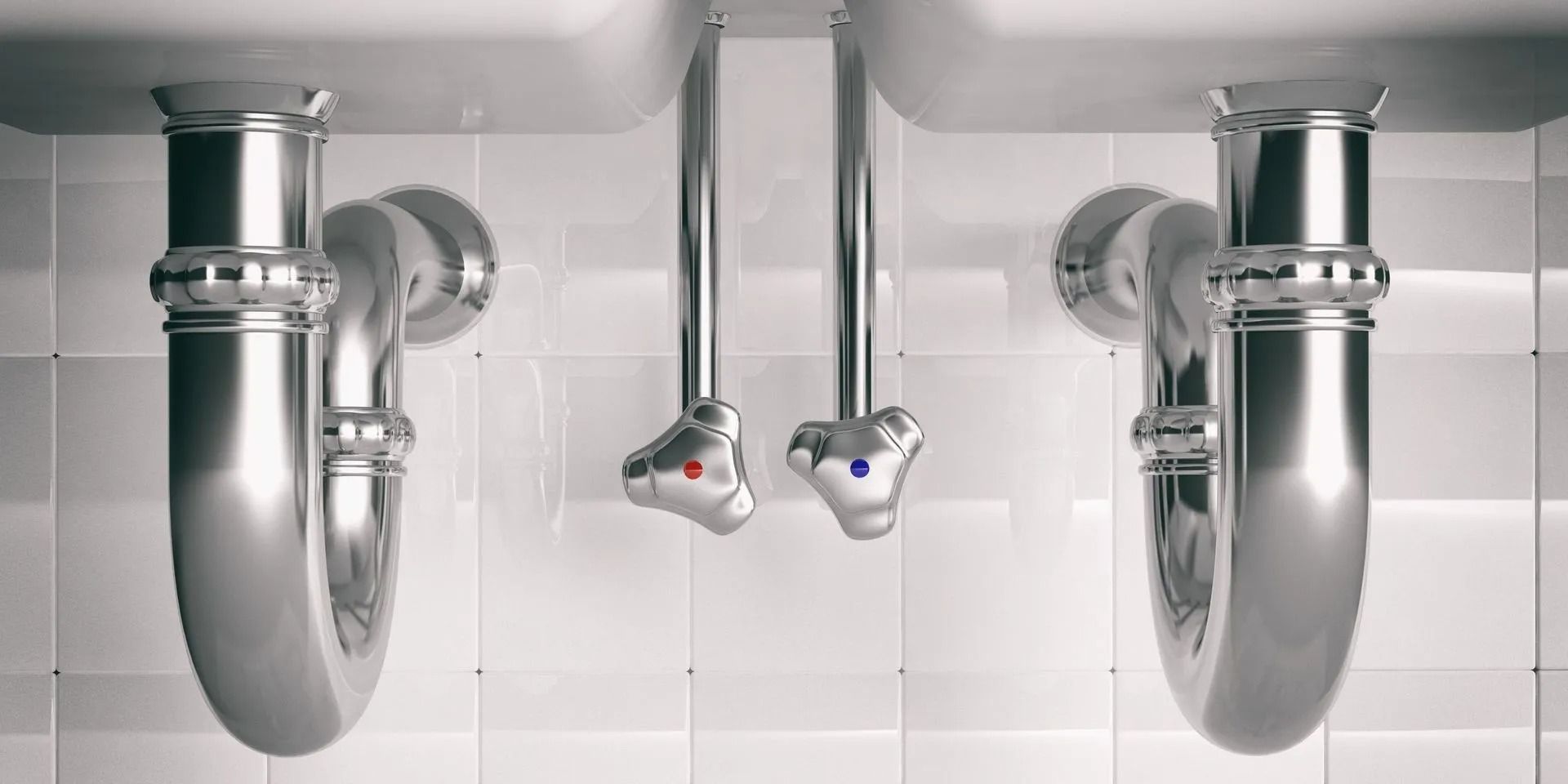 Vista inferiore di due lavandini del bagno con tubi e valvole cromati.