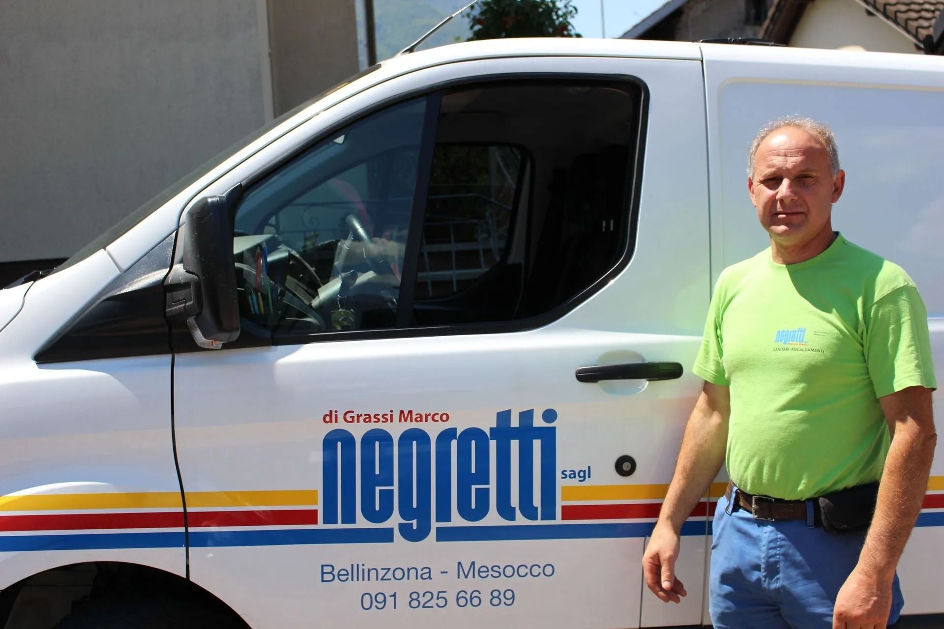 Un uomo con una camicia verde è in piedi accanto a un furgone bianco con il logo 