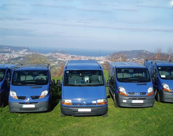 Una fila de furgonetas azules están estacionadas en un campo de hierba.
