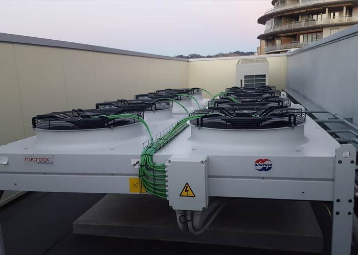 Una fila de aparatos de aire acondicionado están colocados en la parte superior de un edificio.