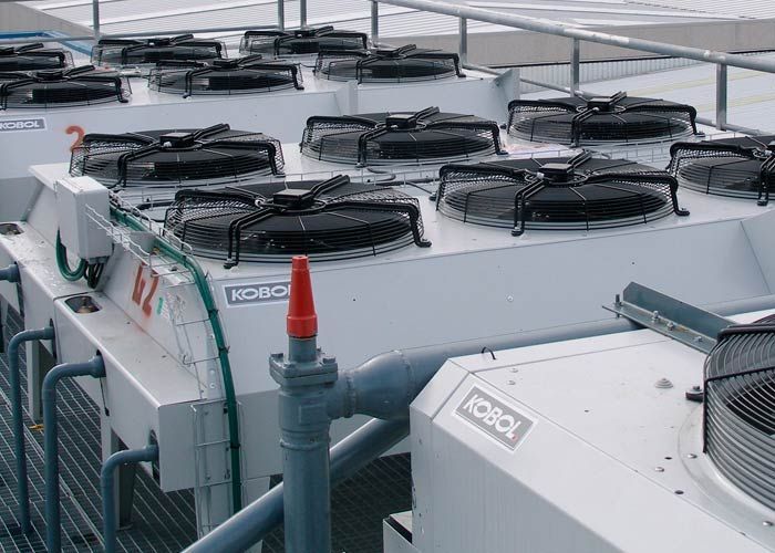 Una fila de aparatos de aire acondicionado blancos están colocados encima de un techo.