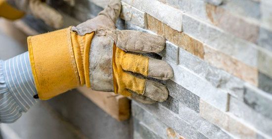 Una persona con guantes está instalando un muro de piedra.