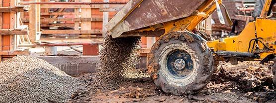 Un camión volquete está cargando tierra en un contenedor de basura en un sitio de construcción.