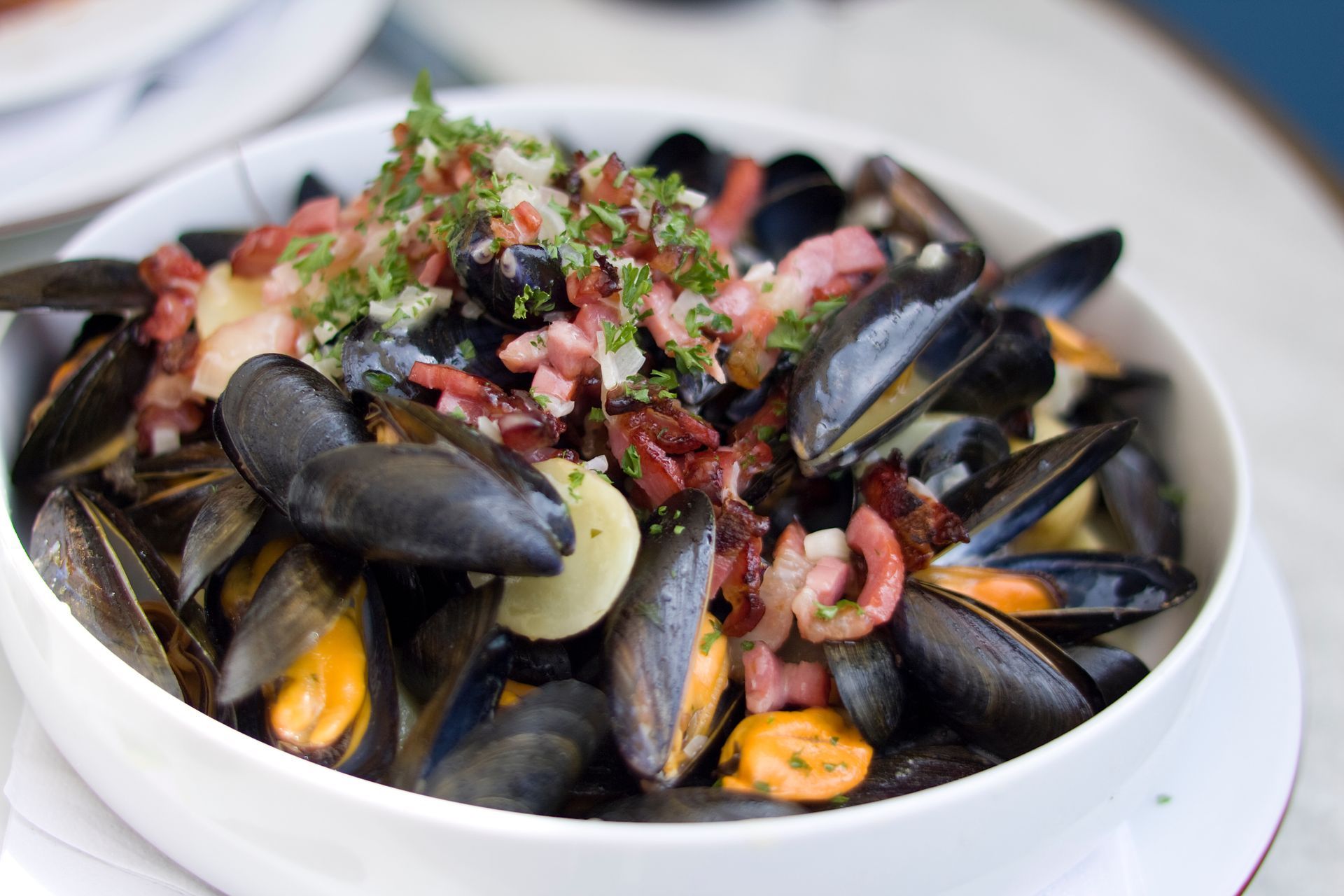 Bol de moules cuites, garni de bacon et d'herbes.