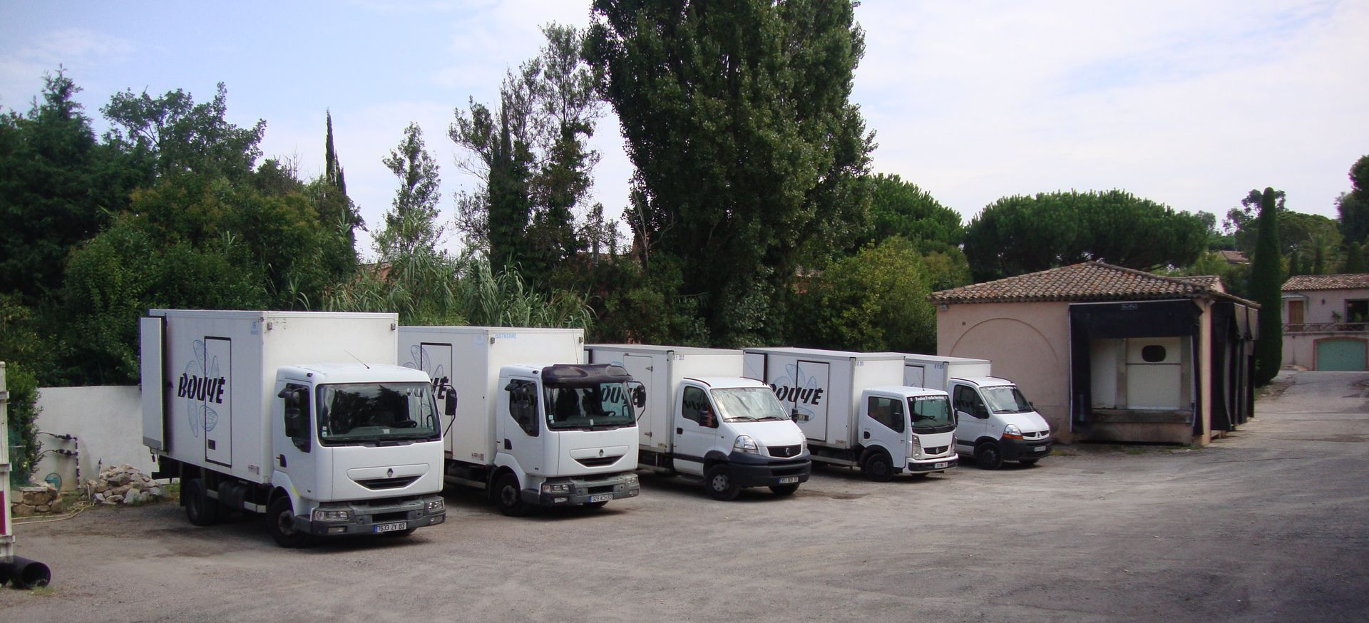 Plusieurs camions de livraison blancs stationnés sur un terrain.