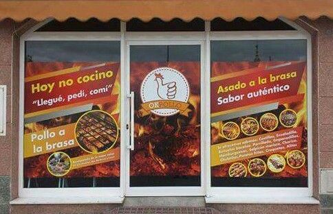 Un restaurante con muchos anuncios en las ventanas.
