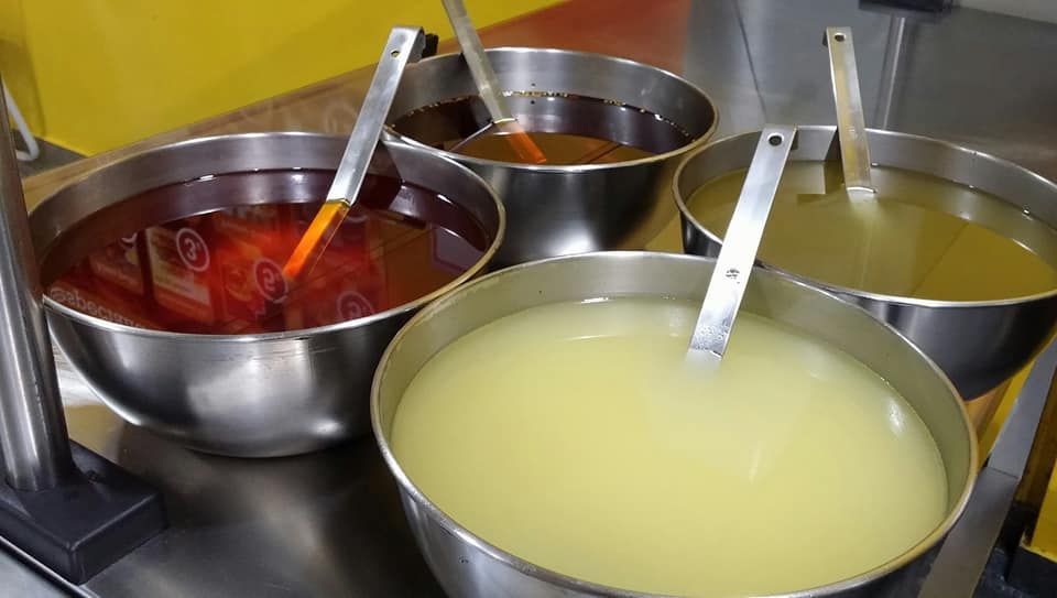 Cuatro cuencos de líquidos de diferentes colores con cucharas en ellos.