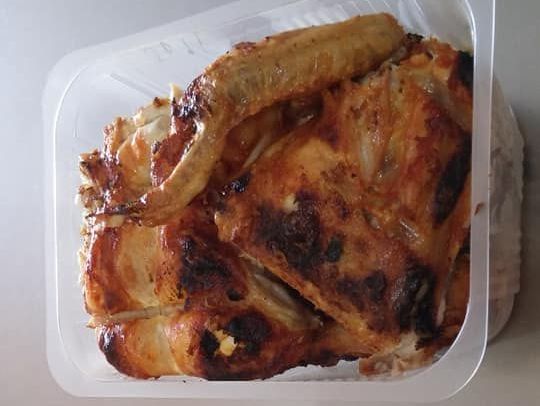 Un recipiente de plástico lleno de alitas de pollo está sobre una mesa.