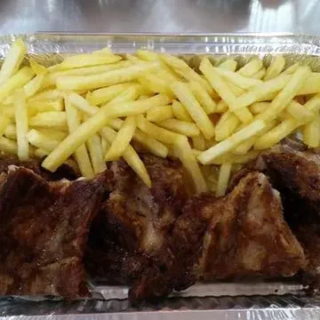 Un recipiente de aluminio lleno de costillas y papas fritas.