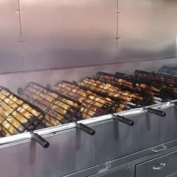 Un montón de comida se está cocinando en una parrilla en una cocina.