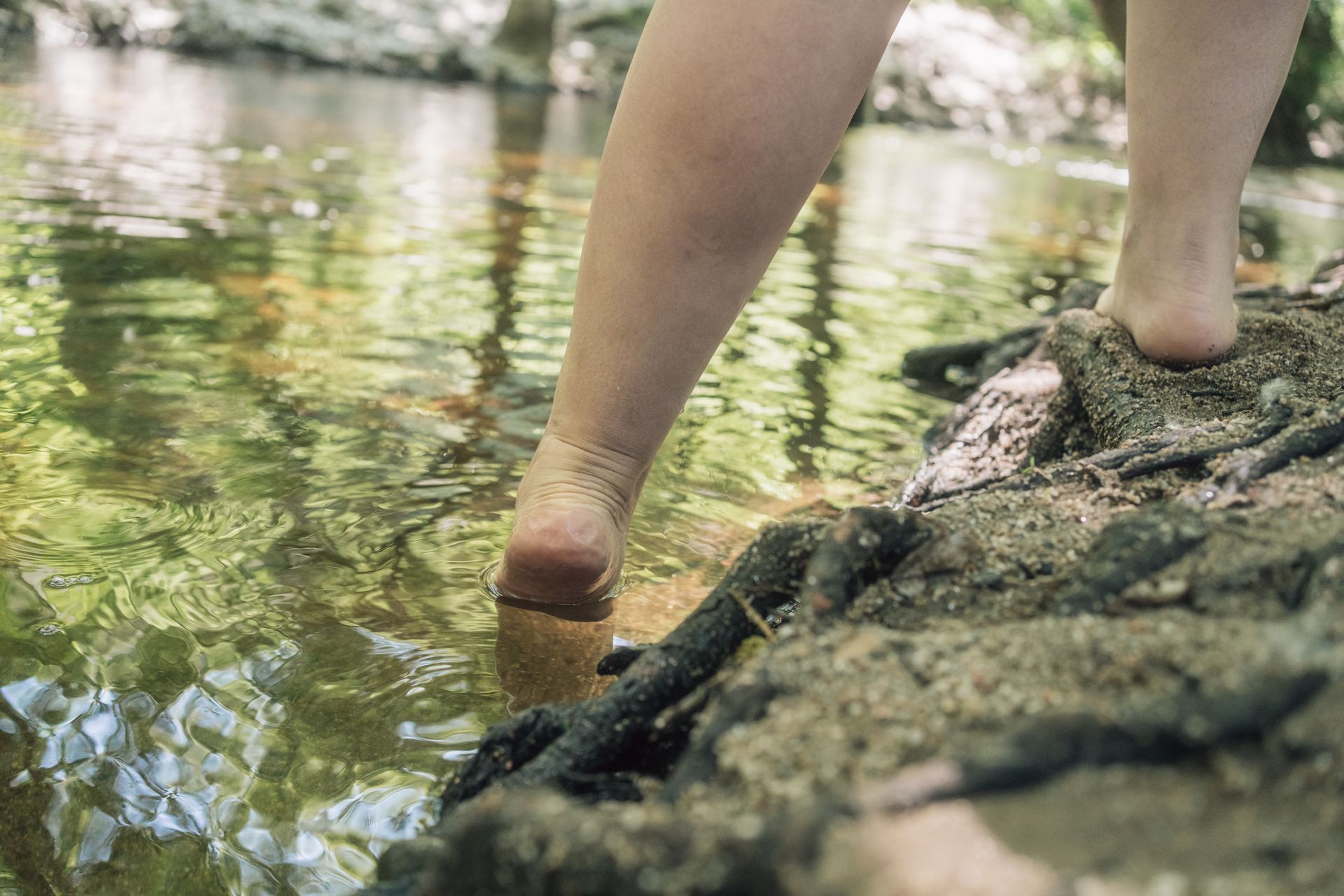 Des pieds nus foulant un ruisseau forestier peu profond.