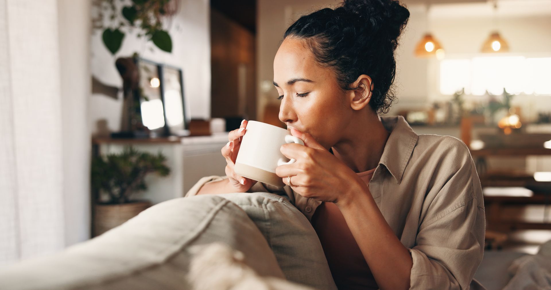 Femme tenant une tasse sur un canapé.