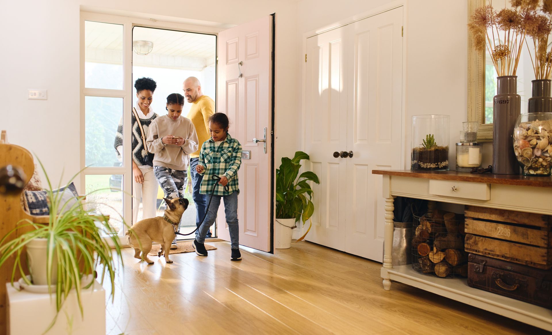 Une famille entre dans une maison lumineuse avec un chien.