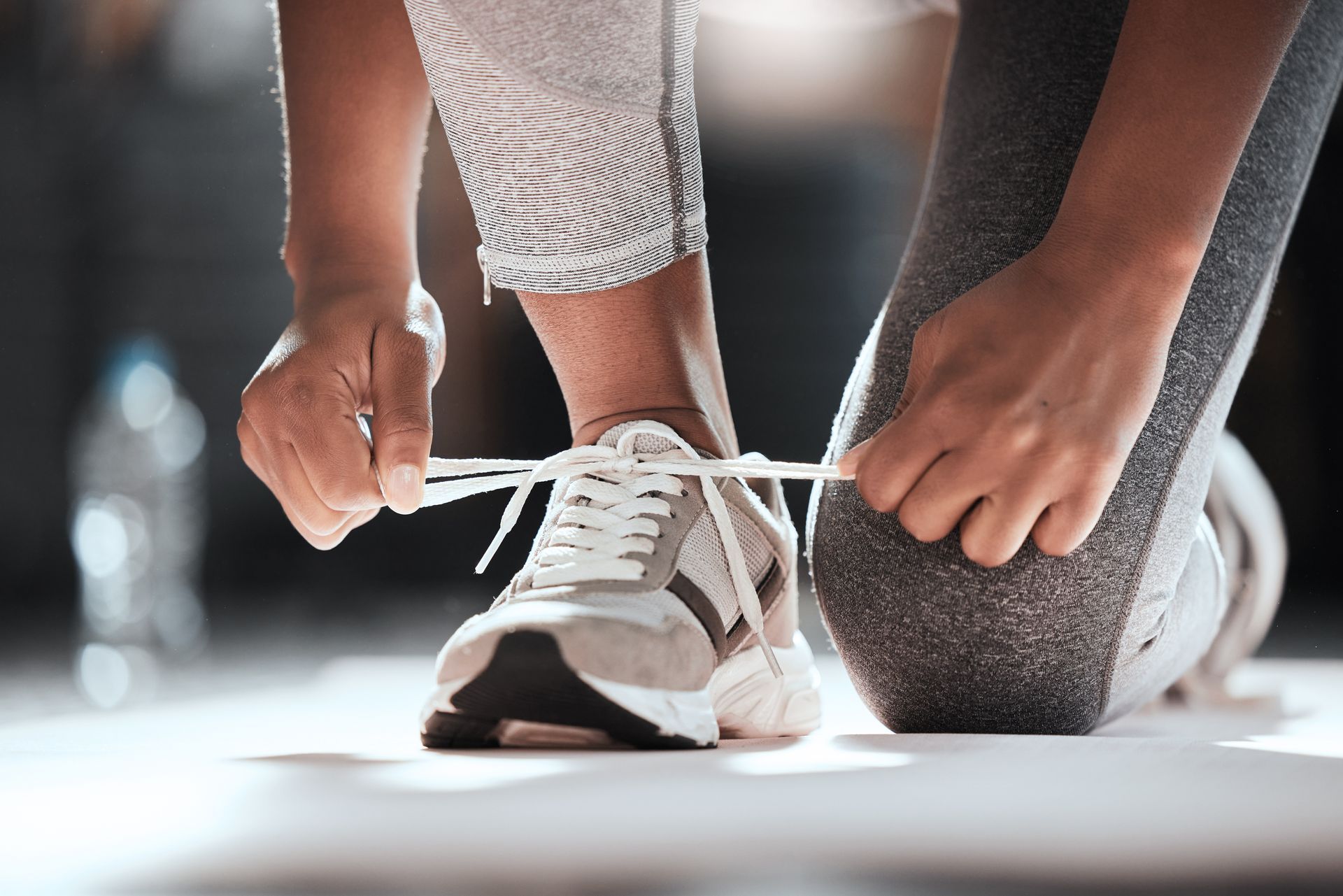 Une personne lace les lacets de ces chaussures de sport.