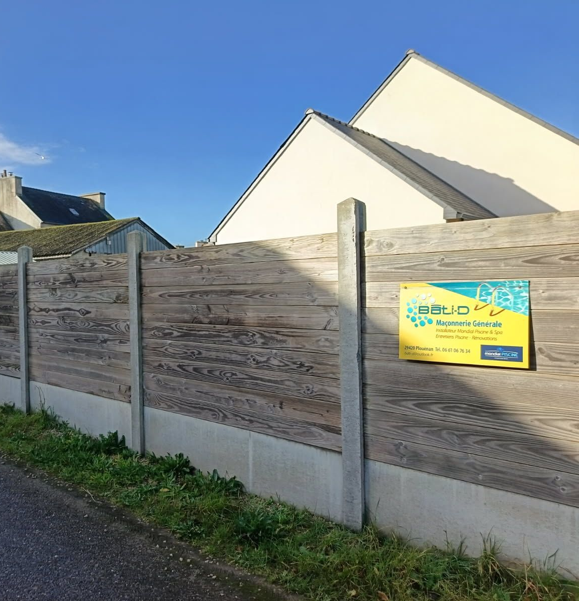 Clôture à lattes horizontales en bois avec panneau publicitaire de la société