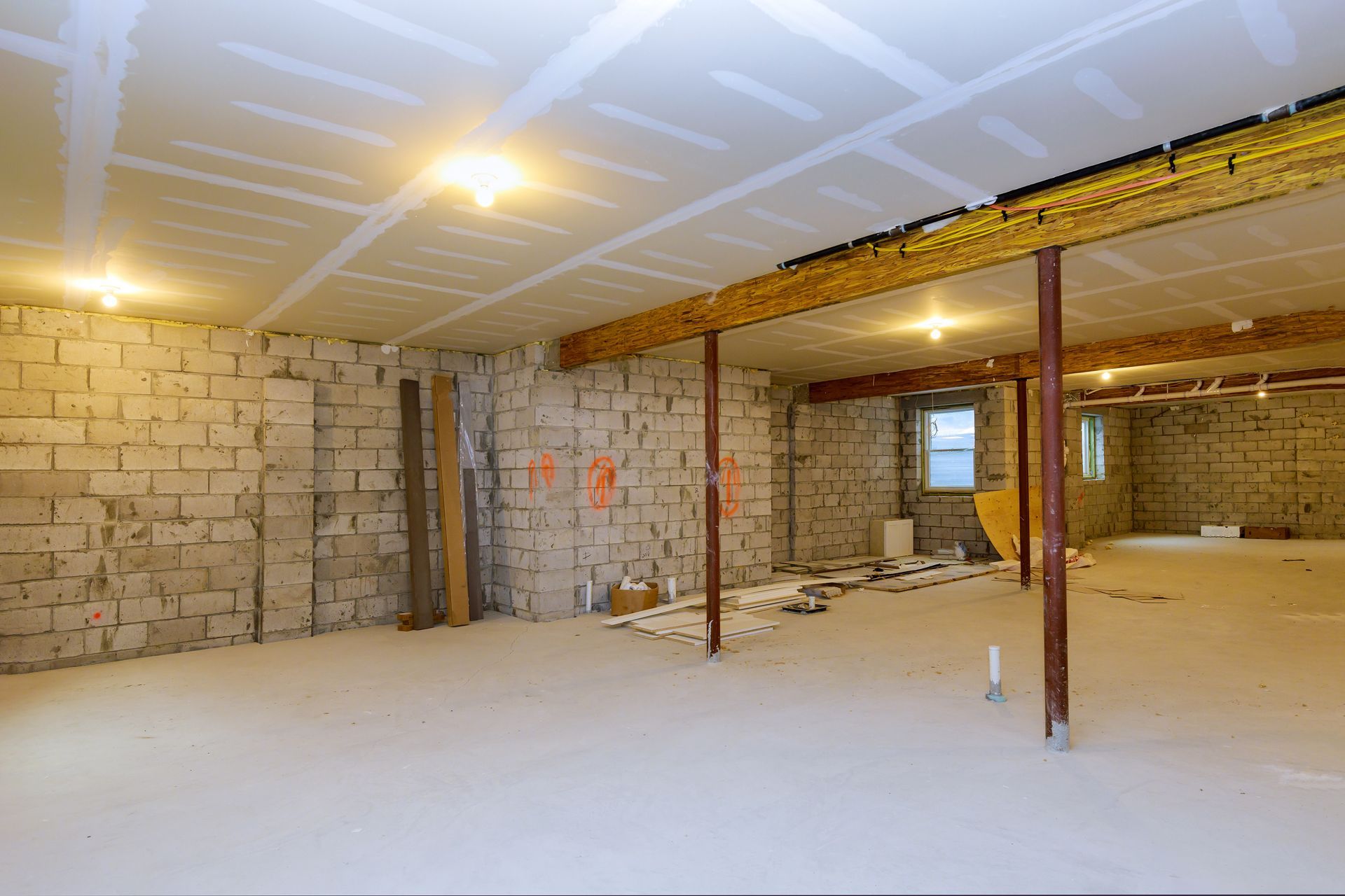 Sous-sol en construction, avec murs en parpaings et poutres de plafond apparents.