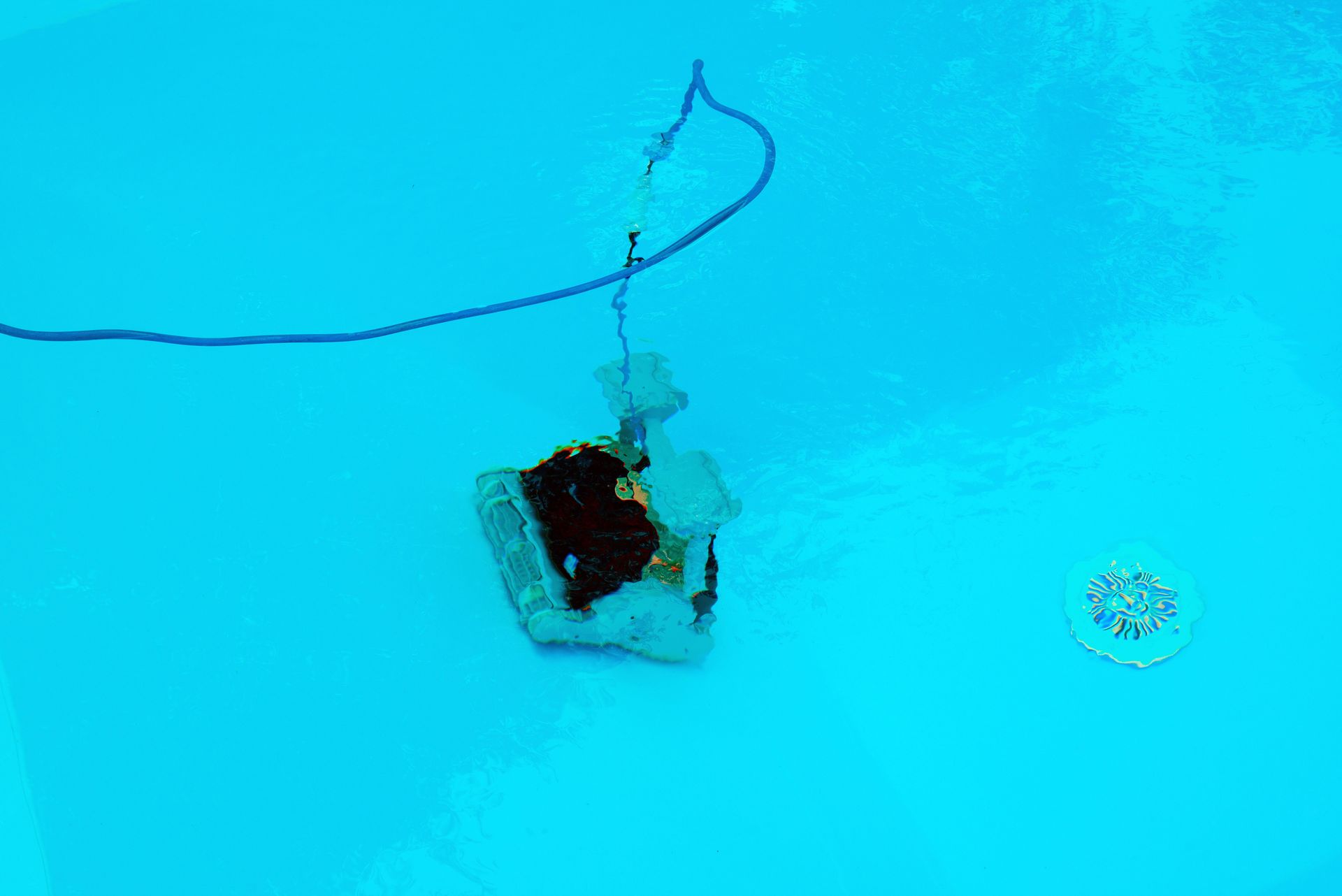 Robot nettoyeur de piscine dans une piscine bleue.