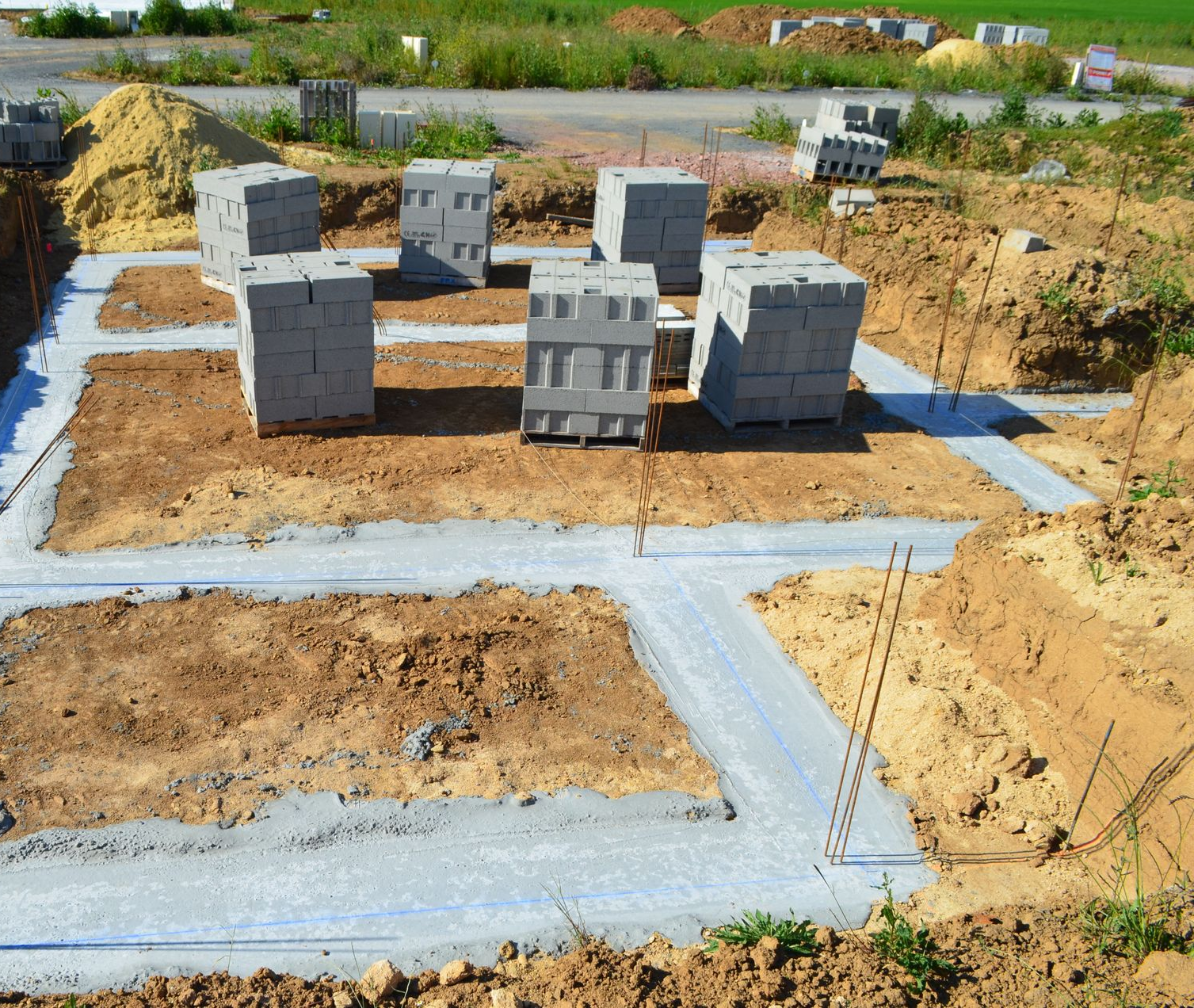 Chantier de construction avec fondations en béton et blocs de béton empilés.