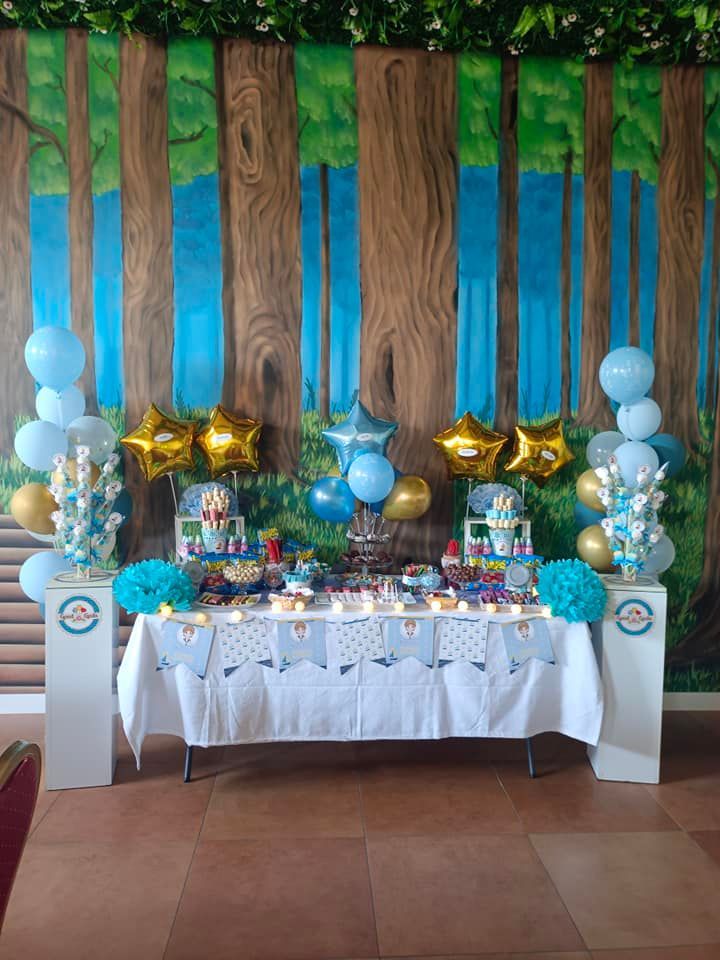 Una mesa con globos y dulces frente a una pared de madera.