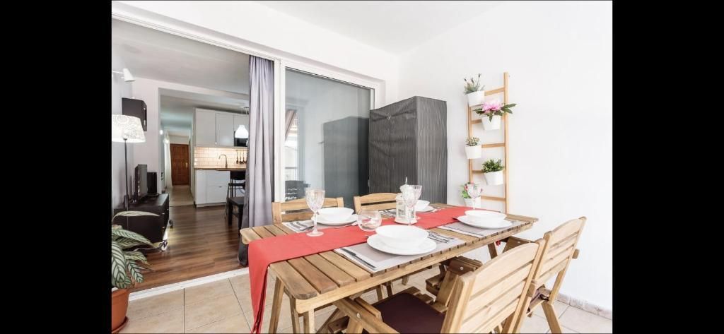 Comedor con la mesa puesta, sillas de madera y vistas despejadas a una sala de estar con puertas correderas de cristal.