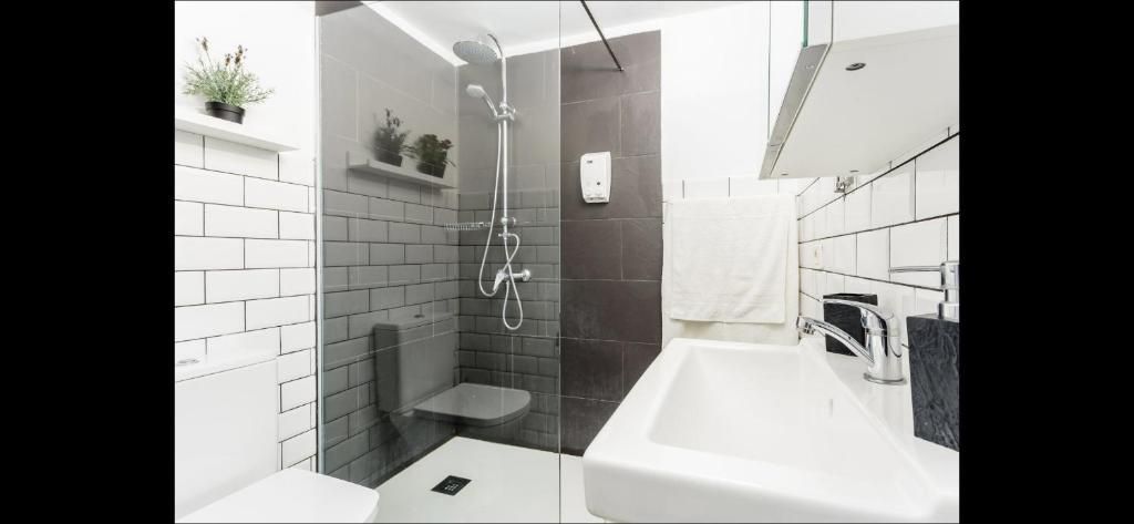 Baño moderno blanco con ducha alicatada, mampara de cristal, lavabo con mueble y estantes de pared