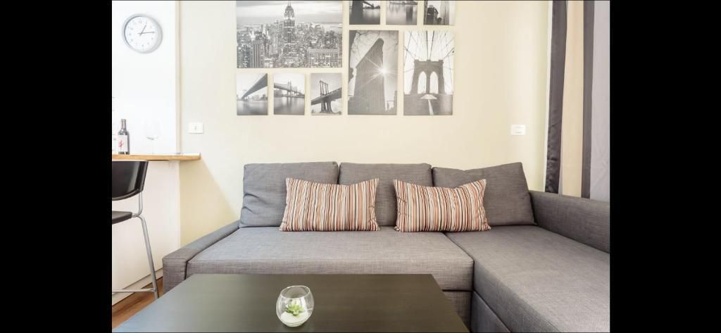 Sofá seccional moderno gris en una sala luminosa, con cuadros en blanco y negro y cojines a rayas