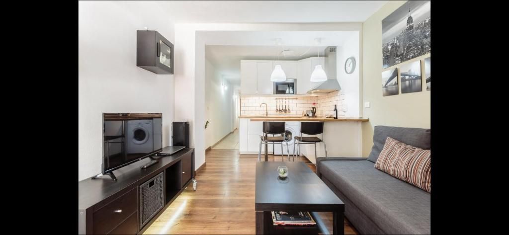 Luminoso salón con sofá, mueble para la televisión, mesa de centro y cocina abierta al fondo