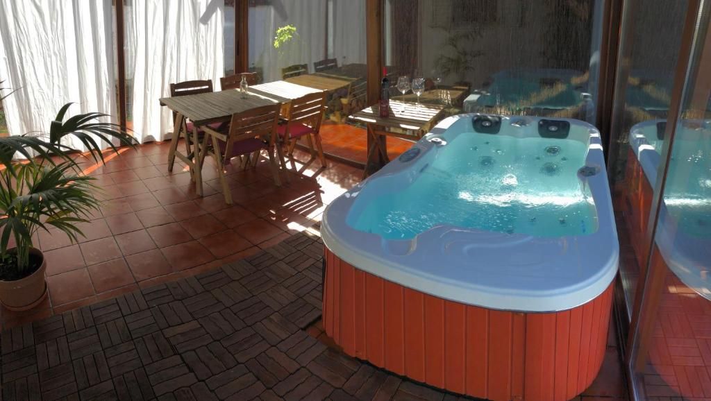 Habitación luminosa con jacuzzi, mesa de comedor, sillas y grandes ventanales con vistas al exterior