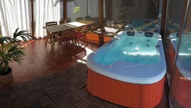 Habitación luminosa con jacuzzi, mesa de comedor, sillas y grandes ventanales con vistas al exterior