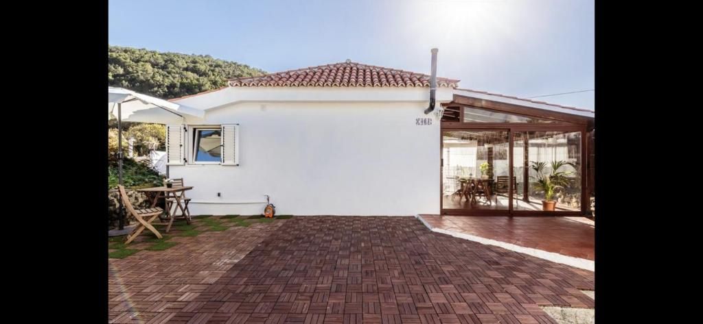 Casa blanca con tejado de tejas y entrada de ladrillo bajo un sol radiante