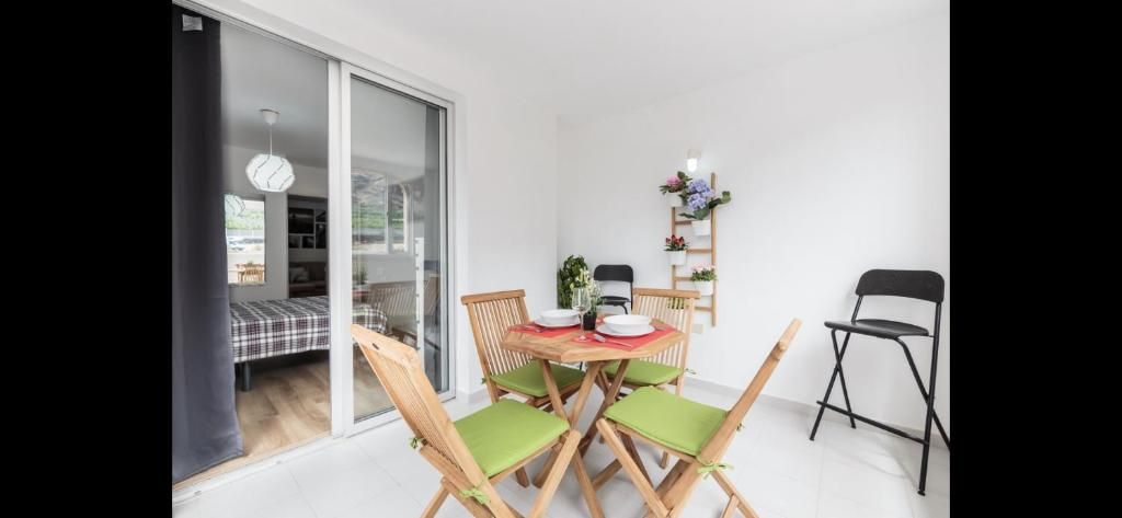 Conjunto de comedor de exterior con sillas de madera y cojines de colores junto a una puerta corrediza de cristal