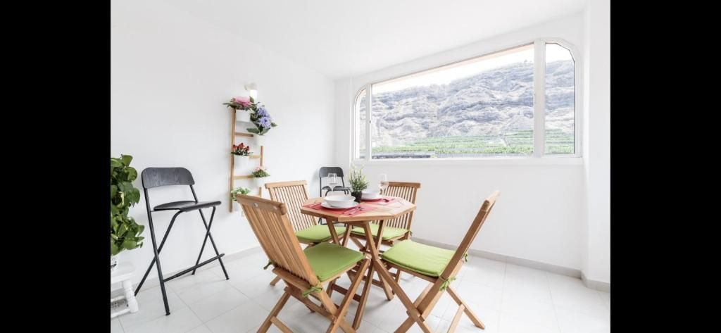 Patio de un blanco luminoso con sillas plegables de madera, una mesa redonda y una gran ventana con vistas a un paisaje nevado