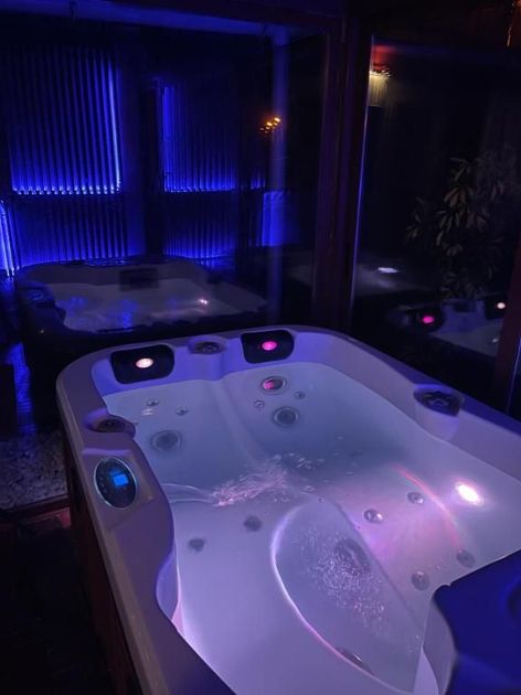 Jacuzzi interior con iluminación azul y agua burbujeante en una oscura sala de spa