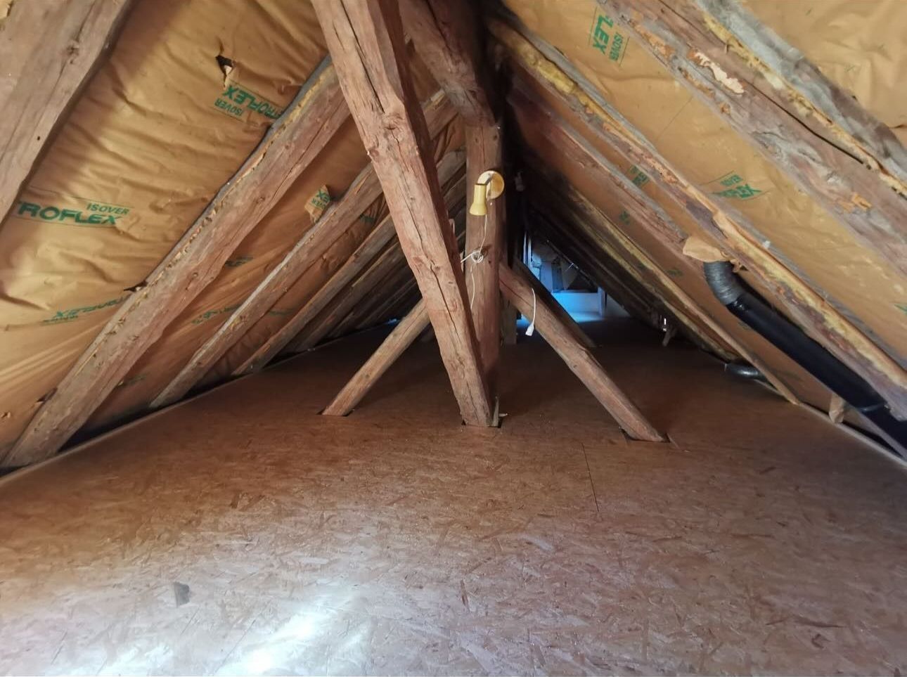 Un intérieur mansardé avec des chevrons en bois et une isolation.