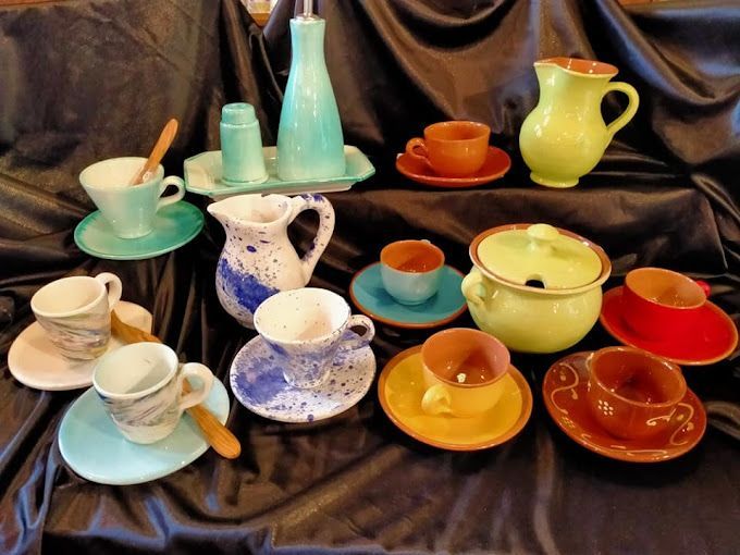 Un montón de tazas y platillos de colores sobre una mesa.