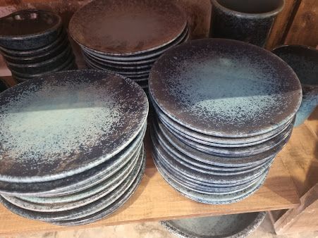 Una pila de platos y cuencos negros en un estante de madera.