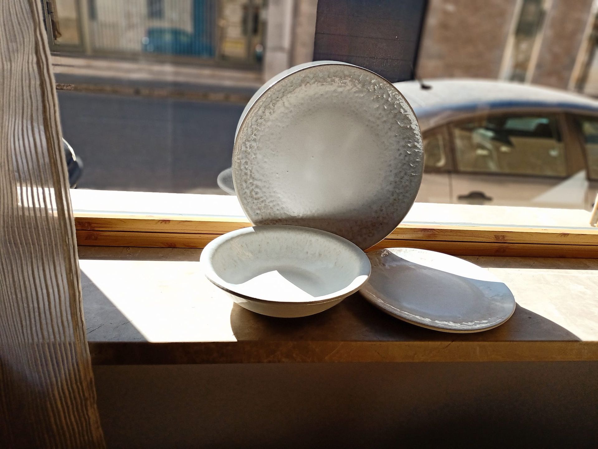 Hay dos cuencos blancos en el alféizar de una ventana.