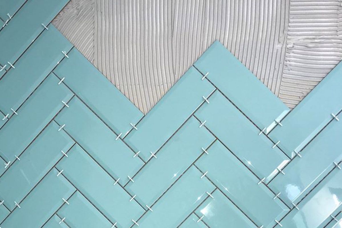 Motif de carreaux à chevrons bleu clair sur fond gris texturé, avec une découpe triangulaire en haut.