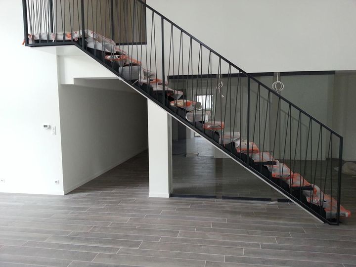 Escalier intérieur avec rampe en métal noir et marches à motifs dans une pièce moderne