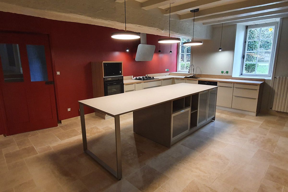 Cuisine moderne avec murs rouges, îlot central blanc, placards en bois et coin évier vitré