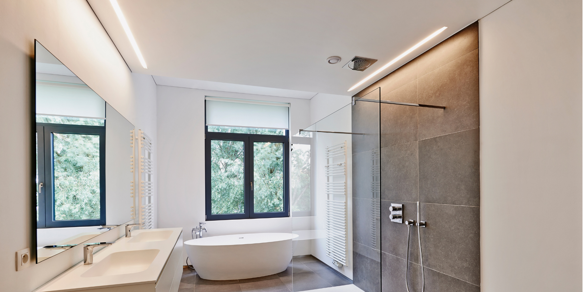 Salle de bain moderne avec un grand miroir, une douche en verre et une baignoire autoportante près d'une fenêtre.