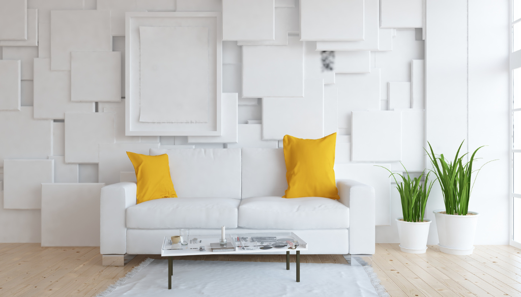 Salon blanc avec canapé, coussins jaunes, table basse, plantes et œuvres d'art murales encadrées.