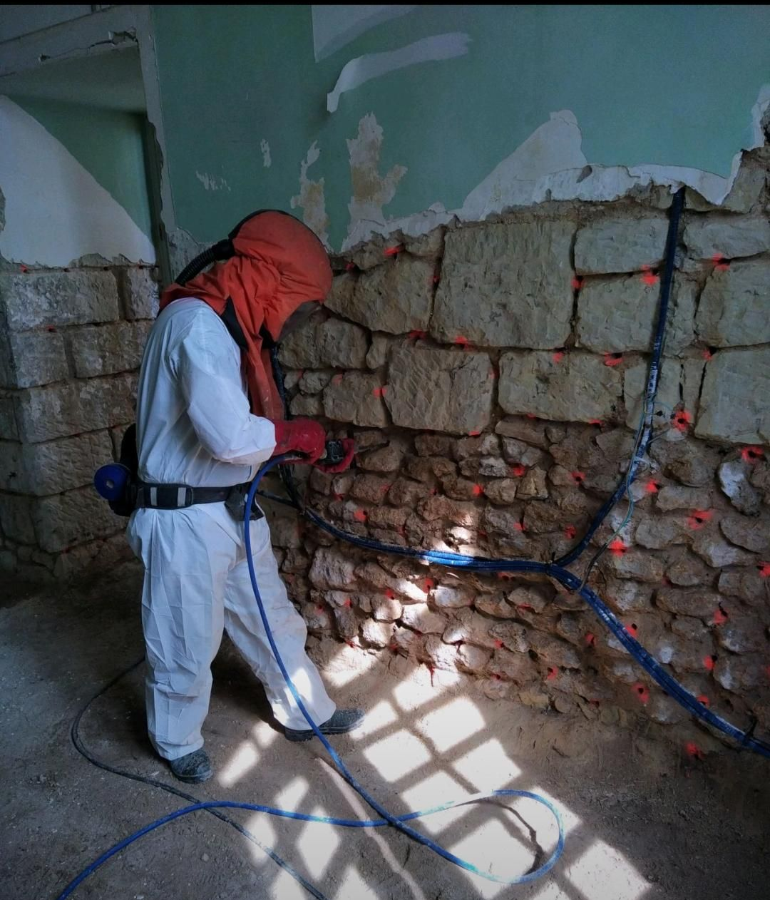 Un technicien de l'entreprise CBTI qui injecte du fongicide dans un mur en pierre pour éradiqué la mérule pleureuse 