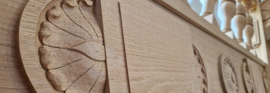 Panneau de rampe en bois clair orné d'une décoration sculptée en forme de rosace.