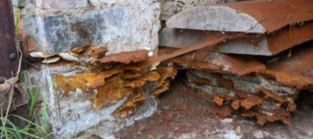 Plusieurs formations brun-orangé à texture stratifiée se développant entre des matériaux de construction empilés.