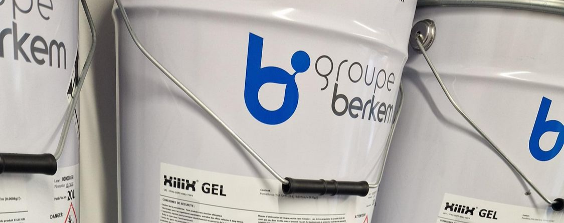 Seaux métalliques blancs portant le logo bleu et noir Groupe Berkem, alignés les uns à côté des autres.