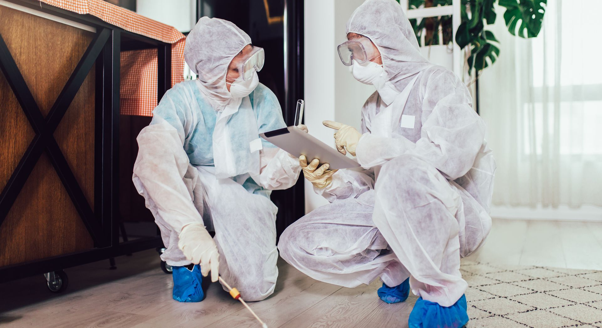Deux personnes portant des combinaisons de protection blanches accroupies