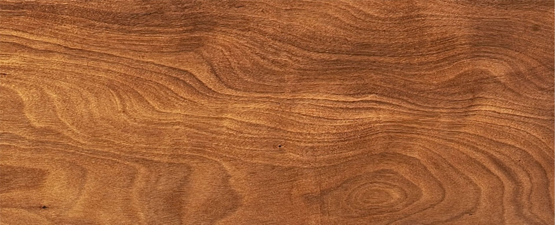 Gros plan sur une surface en bois verni présentant les veines et les motifs naturels du grain du bois.
